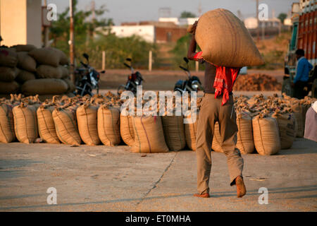 Arbeiter mit Jutetasche mit Getreide auf seinem Kopf an Harsud Mandi; Körner-Lebensmittelmarkt in Bhopal Stockfoto