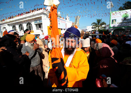 Sikh Anhänger mit Nishansahib Heiligen Fahne während der Prozession der Hola Mohalla in Anandpur Sahib in Rupnagar Stockfoto