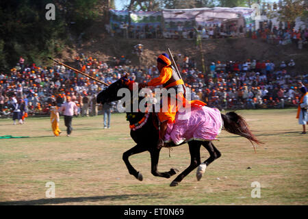 Nihang oder Sikh Krieger mit Speer und Gewehr Reiten auf Pferd während Hola Mohalla Festivals bei Anandpur Stunts ausführen Stockfoto