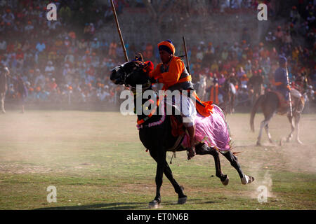 Nihang oder Sikh Krieger mit Speer und Gewehr Reiten auf Pferd während Hola Mohalla Festivals bei Anandpur Stunts ausführen Stockfoto