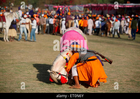 Nihang oder Sikh Krieger mit Gewehr und Pferd während der Hola Mohalla Feier bei Anandpur Sahib in Rupnagar Stockfoto