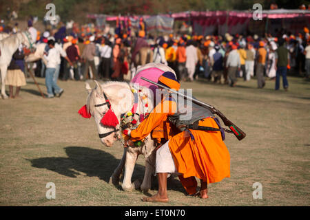 Nihang oder Sikh Krieger mit Gewehr und Pferd während der Hola Mohalla Feier bei Anandpur Sahib in Rupnagar Stockfoto