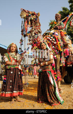 Mädchen in traditionellen Schmuck und Rajasthani Kostüm vor geschmückten Kamel in Pushkar fair; Rajasthan Stockfoto