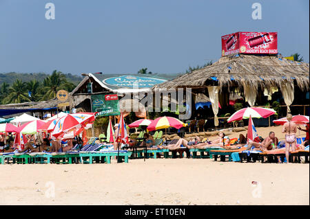 Große Sonnenschirme und Holzbetten in Calangute Beach; Goa; Indien Stockfoto