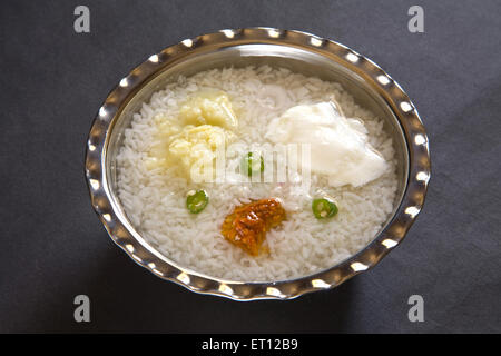 Indische Mittagessen Pakhala Reis Gurke Maische Kartoffel mit Chili und Joghurt in Stahl Schüssel auf schwarzem Hintergrund 15. April 2010 Stockfoto