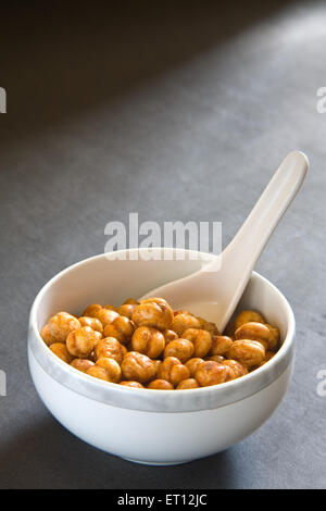 Indisches Frühstück Braten Kichererbsen Chana Masala in Schüssel serviert mit Löffel auf schwarzem Hintergrund 12. Mai 2010 Stockfoto