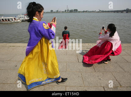 Dandong, LIAONNG Provinz, CHINA. 27. Mai 2015. Ein chinesisches Ehepaar stellt für Hochzeitsfotos, wie Handel mit Nordkorea (Hintergrund) und auf der Friendship Bridge (R) in Dandong, Chinas größere Grenzstadt mit Nordkorea in der Liaoning Provinz, China am 27. Mai 2015 weiter. China bleibt wichtigster Verbündeter Nordkoreas, Bereitstellung von Pyongyang mit den größten Teil seiner Nahrung und Energie liefert und umfasst mehr als 60 Prozent seiner gesamten Handelsvolumen. Wirtschaftliche Abhängigkeit Nordkoreas von China wächst weiter durch internationale Sanktionen, wie durch die bedeutenden Handelsungleichgewicht zwischen Stockfoto