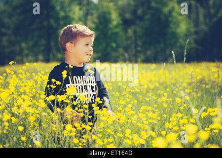 kleine süße junge Kind in einem wunderschönen gelben Blüten, Lächeln und lachen Stockfoto