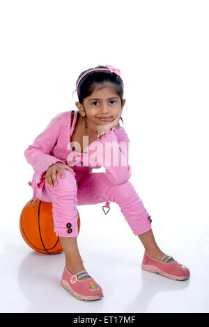 Indische Mädchen sitzen auf Fußball auf weißem Hintergrund - Model Release # 736 M Stockfoto