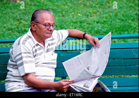 Indische älterer Bürger lesen Zeitung sitzen grüne Garten Bank Herr Nr. 364 Stockfoto