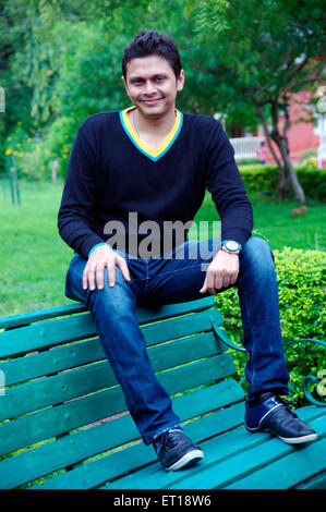 Indischen jungen Mann sitzt Park Bench blau Jeans - Model Release # 782W Stockfoto