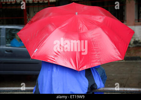 Mann in blauem Kunststoff Regenmantel mit roten Regenschirm HERR Nr. 364 Stockfoto