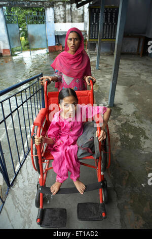 Frau schieben Rollstuhls körperlich behinderte Tochter sozio-wirtschaftliche Initiative von NGO Chinmaya Organisation Stockfoto