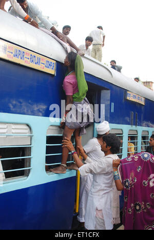 Männer ziehen Frau versucht, Klettern auf dem Dach des Zuges in Jodhpur station Rajasthan Indien Stockfoto