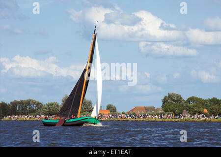 Eine historische Flachboden-Boot segelt auf einem der Seen in Friesland mit Zuschauern Skutsjesilen in Holland Stockfoto