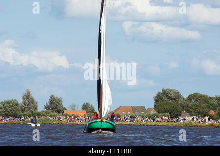 Eine historische Flachboden-Boot segelt auf einem der Seen in Friesland mit Zuschauern Skutsjesilen in Holland Stockfoto