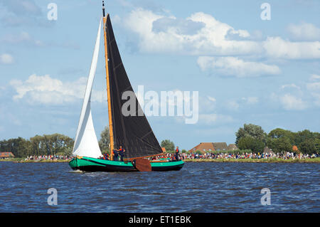 Eine historische Flachboden-Boot segelt auf einem der Seen in Friesland mit Zuschauern Skutsjesilen in Holland Stockfoto