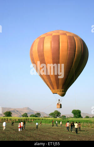 Braun bunt gestreiften Heißluftballon fliegen über Zuckerrohr Betriebe; Wai; Maharashtra; Indien Stockfoto