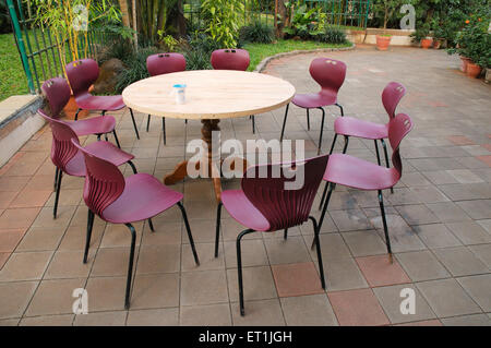 Runder Holztisch mit zehn Plastikstühlen im Garten Stockfoto