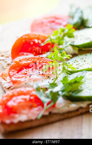 Gesunde Ernährung. Hellen Frühstück Sandwiches. Finnische Roggen Knäckebrot, Weichkäse, Gurken, Tomaten, Petersilie und Pfeffer Stockfoto