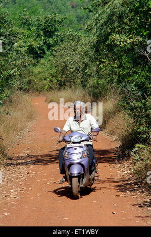 Mann auf Roller und rote Erde Road Konkan Maharashtra Indien Herr #556 Stockfoto