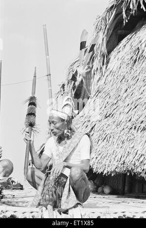 Wancho Stammesälterer in traditioneller Kleidung, die Speer vor seinem Haus hält; Senua; Tirap; Arunachal Pradesh; Indien; Asien; alter Jahrgang 1900er Jahre Stockfoto