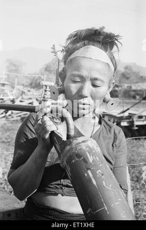 IDU Mishmi Dame, die Bambuspfeife mit Wasser füllt; Hill Miri Tribe; Subansiri; Kamle; Arunachal Pradesh; Indien; Asien ; alter Jahrgang 1900s Bild Stockfoto