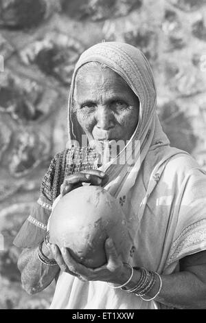 Dorffrau trinkt zartes Kokoswasser am Stadtrand von Pune; Maharashtra; Indien; Asien; alter Jahrgang 1900er Jahre