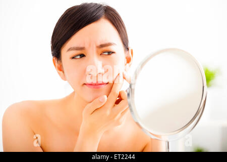 junge Frau Squeezing Pickel auf Spiegel Stockfoto