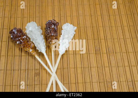 Zwei Zuckersticks mit weißer und brauner Zucker gegen ein Holztisch Stockfoto