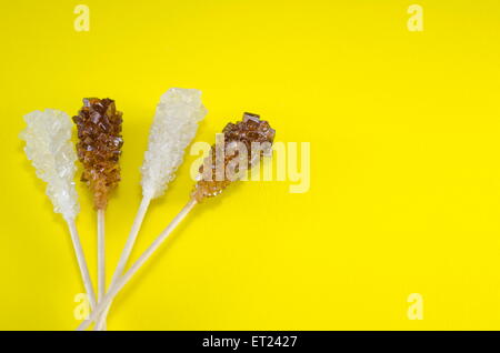 Zwei Zuckersticks mit weißen und braunen Zucker mit gelbem Hintergrund Stockfoto