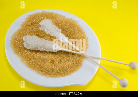 Zwei Zuckersticks mit weißen und braunen Zucker mit gelbem Hintergrund Stockfoto