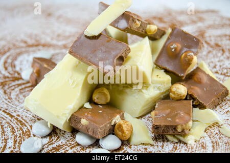 Schwarze und weiße Schokolade Würfel auf einem Kakao bestreut Tisch Stockfoto