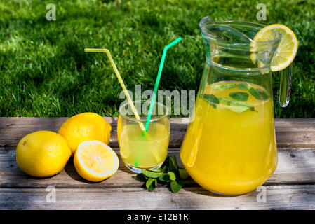 Limonade in den Krug und Zitronen auf dem Tisch im freien Stockfoto