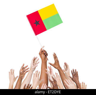 Gruppe von multi-ethnischen Menschen erreichen und die Flagge von Guinea Bissau. Stockfoto