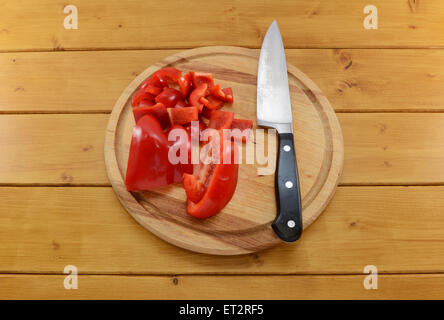 Rohe Paprika in Scheiben geschnitten und mit einem scharfen Küchenmesser auf ein Schneidbrett aus Holz gewürfelt Stockfoto