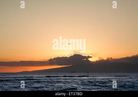 Honolulu, Hawaii. 4. Juni 2015. Sonnenuntergang am Nachmittag mit Flugzeug und Surfer in Waikiki, Honolulu, Oahu, Hawaii. Stockfoto