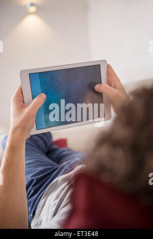 Mann auf der Couch liegend und mit Hilfe einer digitalen-Tablets, München, Bayern, Deutschland Stockfoto