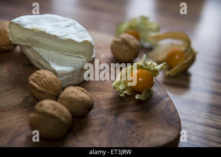 Nahaufnahme der beiden Hälften des Käse und Walnüssen mit einem Kap-Stachelbeere, Deutschland Stockfoto