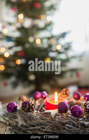 Dekorativer Adventskranz mit brennender Kerze vor dem weihnachtsbaum, Bayern, Deutschland Stockfoto