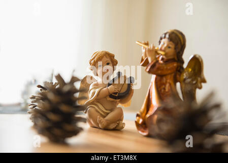 Dekorative weihnachtsengelfiguren mit Musikinstrumenten und Tannenzapfen auf dem Tisch, Bayern, Deutschland Stockfoto