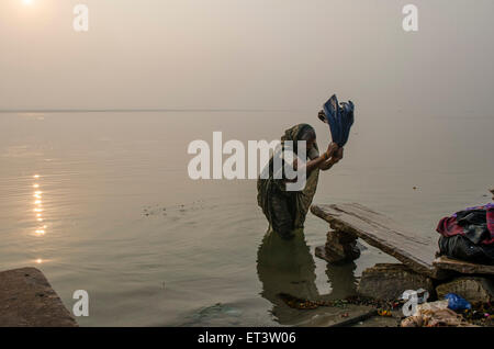 eine Frau wäscht ihre Kleidung an den Ufern des Ganges in Varanasi Stockfoto