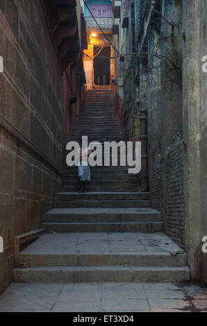 ein Mann steigt die Schritte in Richtung der Angst Ghats am Ufer des Flusses Ganges in Varanasi Stockfoto