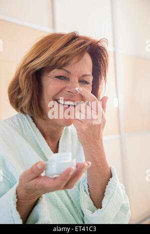 Ältere Frau anwenden Feuchtigkeitscreme im Gesicht, München, Bayern, Deutschland Stockfoto