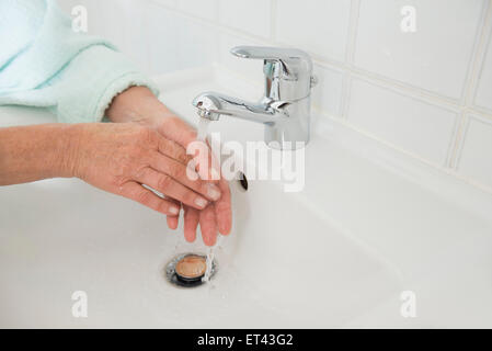 Ältere Frau Händewaschen in Waschbecken, München, Bayern, Deutschland Stockfoto