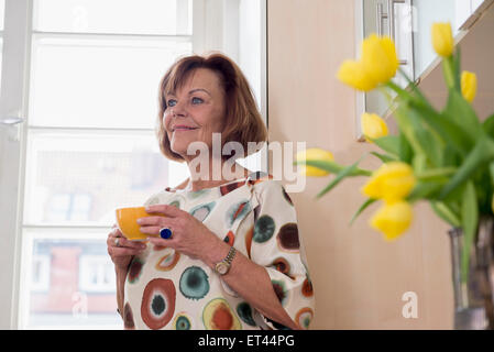 Ältere Frau träumen während des Teetrinkens in Küche München, Bayern, Deutschland Stockfoto