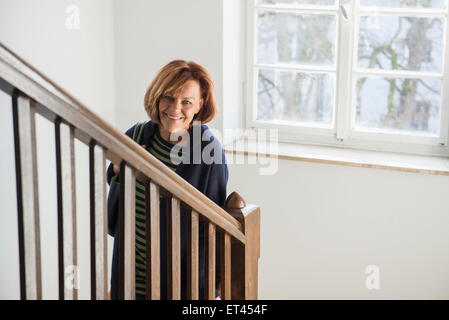 Glücklich senior Trägerin Wintermantel nach unten bewegen, auf einer Treppe, München, Bayern, Deutschland Stockfoto