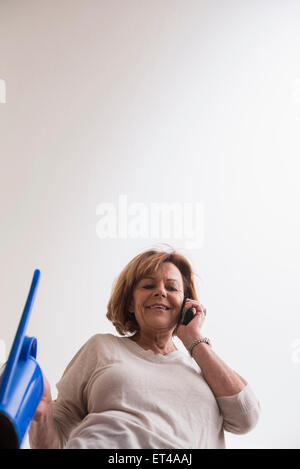 Beautiful senior Woman telefonieren mit Handy und halten eine Gießkanne, Munich, Bavaria, Germany Stockfoto