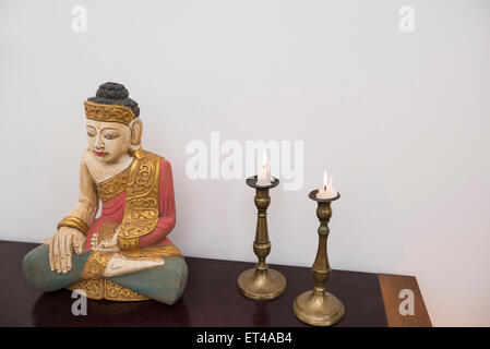Buddha-Statue im Lotussitz mit zwei Kerzen, München, Bayern, Deutschland Stockfoto