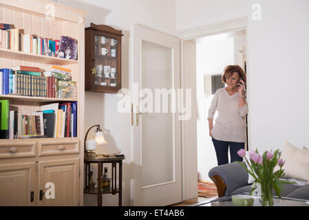 Ältere Frau am Handy an Tür, München, Bayern, Deutschland Stockfoto